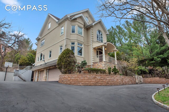 view of property exterior with an attached garage, driveway, stucco siding, and stairway