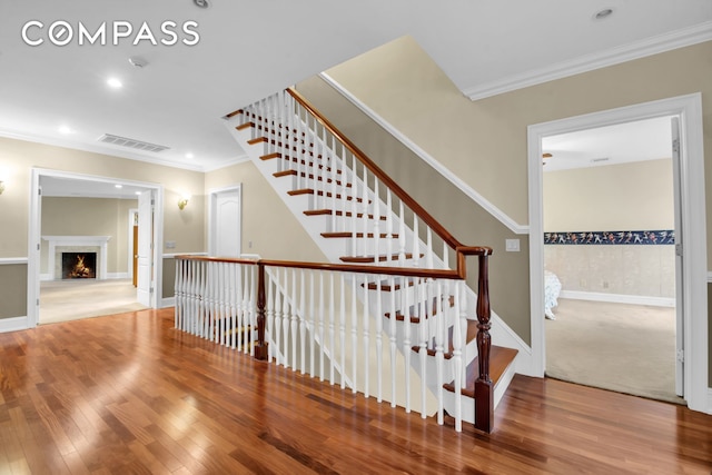 staircase featuring recessed lighting, visible vents, ornamental molding, and wood finished floors