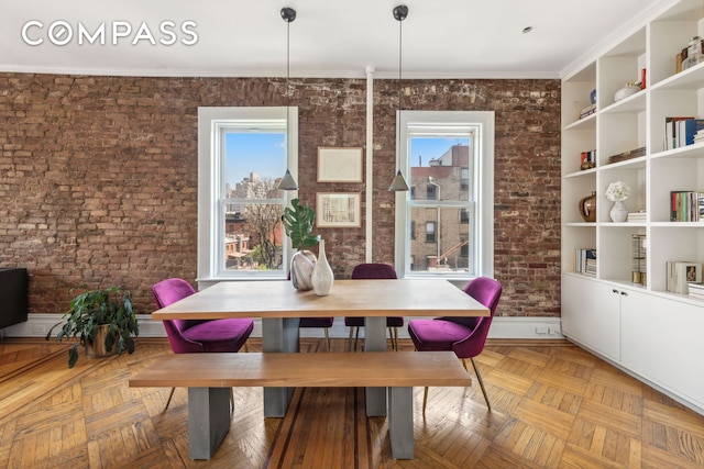dining space with brick wall, ornamental molding, and a healthy amount of sunlight