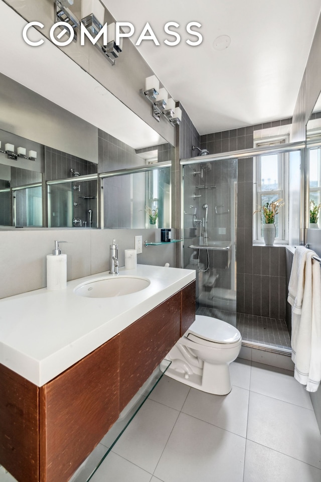 full bathroom featuring vanity, tile patterned floors, a stall shower, and toilet