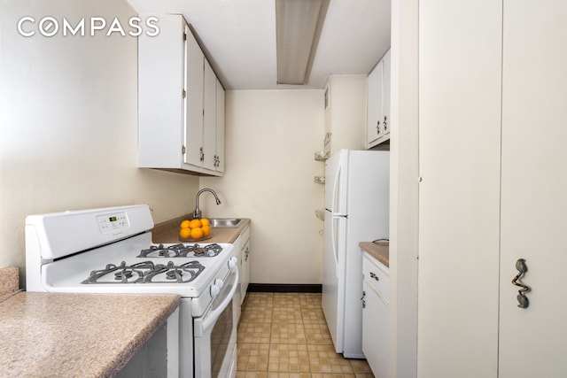 kitchen featuring a sink, light countertops, white cabinets, light floors, and white appliances