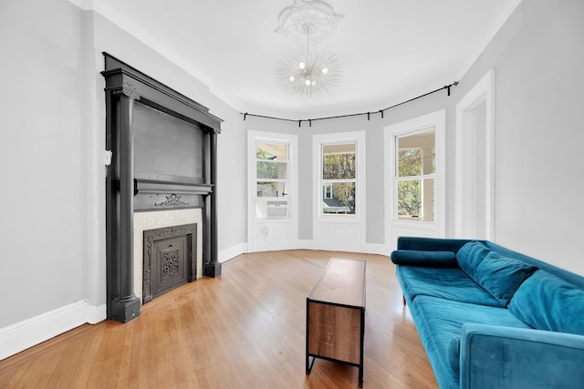 living room featuring a notable chandelier, cooling unit, a fireplace, baseboards, and wood finished floors