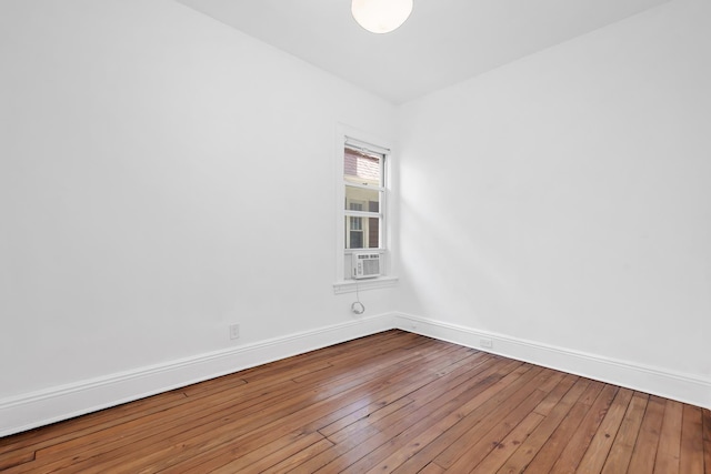 empty room featuring wood-type flooring, baseboards, and cooling unit