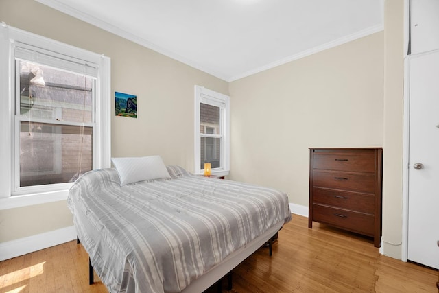 bedroom with crown molding, baseboards, and light wood-style floors