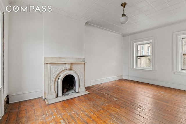 unfurnished living room featuring crown molding, baseboards, a fireplace, and hardwood / wood-style flooring