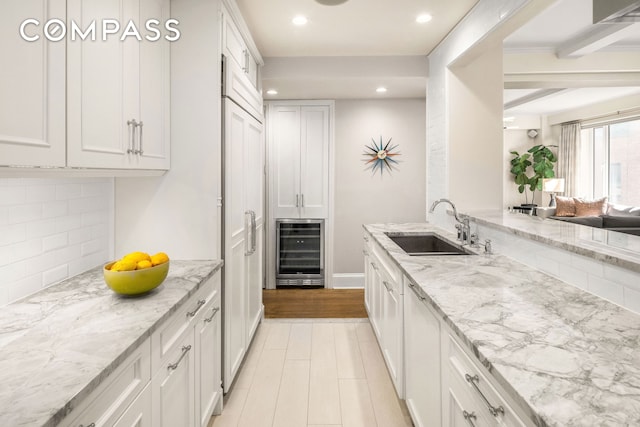 kitchen featuring tasteful backsplash, a sink, beverage cooler, recessed lighting, and white cabinetry