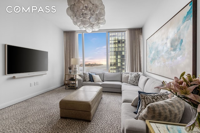 living room featuring carpet floors, baseboards, a chandelier, and a wall of windows