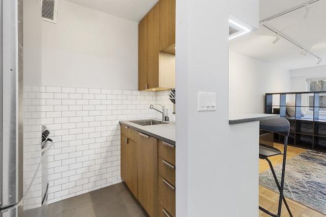101 W 12th St Unit 3C, New York City, NY 10011 - kitchen featuring track lighting, a sink, modern cabinets, brown cabinetry, and a breakfast bar