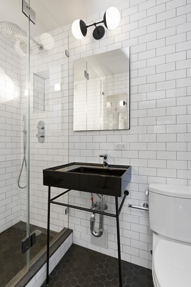 full bath with toilet, tile walls, tile patterned flooring, and a stall shower