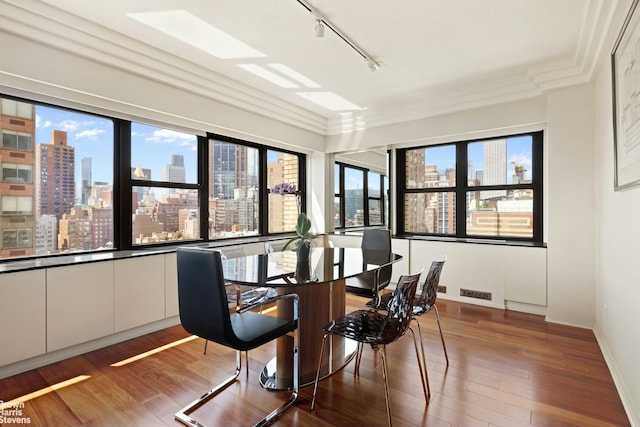 dining area featuring track lighting, a view of city, baseboards, wood finished floors, and visible vents