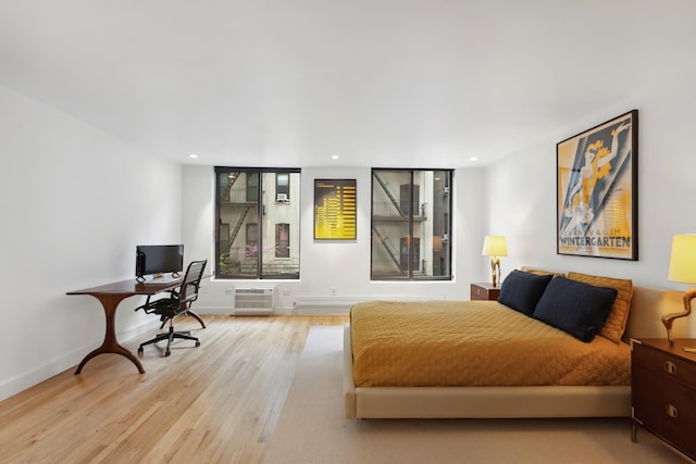 bedroom featuring recessed lighting, baseboards, a wall unit AC, and wood finished floors