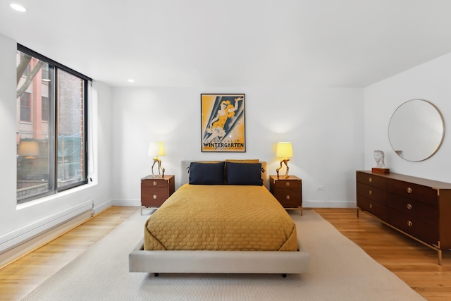 bedroom featuring baseboards, a baseboard heating unit, recessed lighting, and wood finished floors