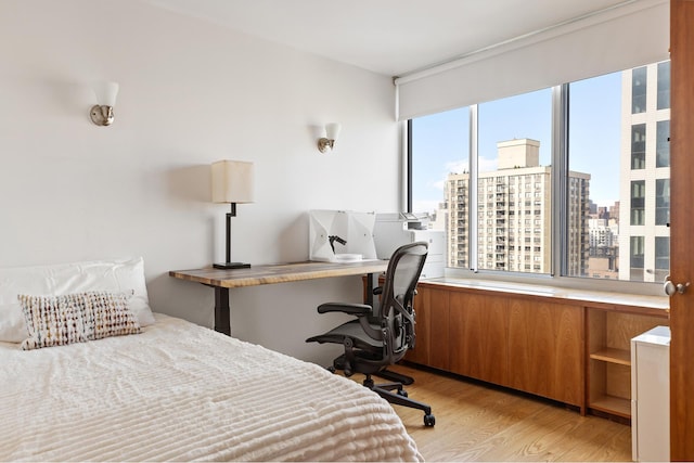 bedroom with light wood-type flooring and a city view