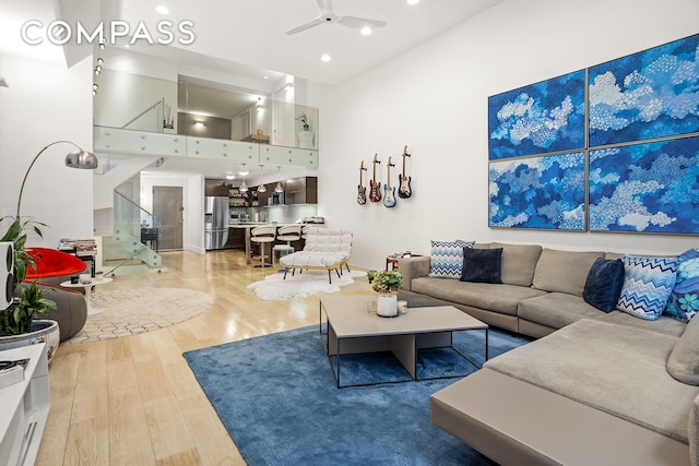 living area with light wood-type flooring, a ceiling fan, and recessed lighting