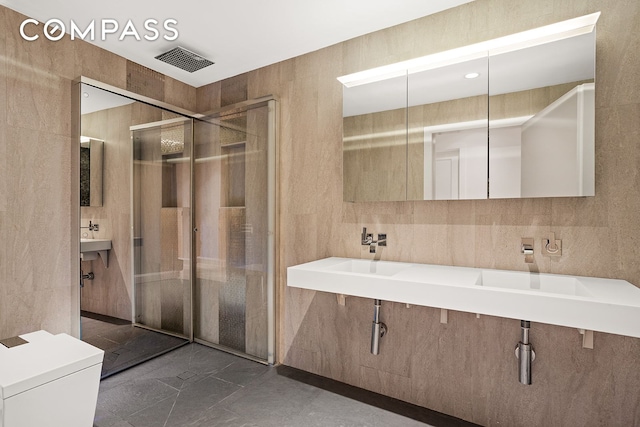 full bathroom featuring tile walls, a shower stall, and visible vents