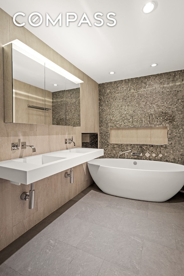 bathroom featuring recessed lighting, tile walls, a soaking tub, and vanity