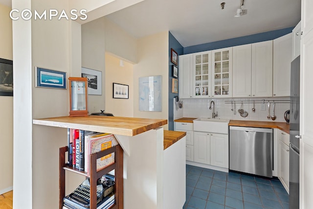 kitchen featuring a sink, stainless steel dishwasher, butcher block counters, and white cabinetry