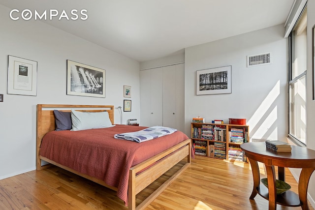 bedroom featuring light wood-style floors, baseboards, a closet, and visible vents