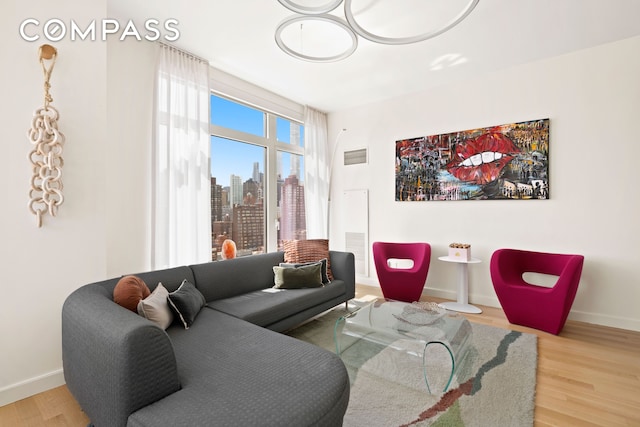 living room with a view of city, baseboards, visible vents, and wood finished floors