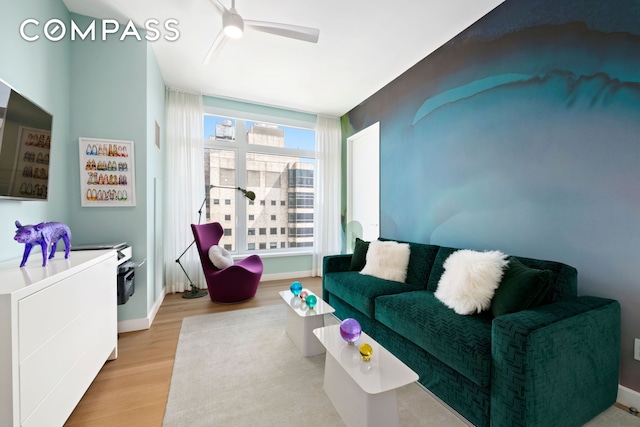 living area with baseboards, ceiling fan, and wood finished floors