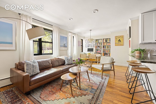 living room featuring crown molding, light wood-style flooring, baseboards, and baseboard heating
