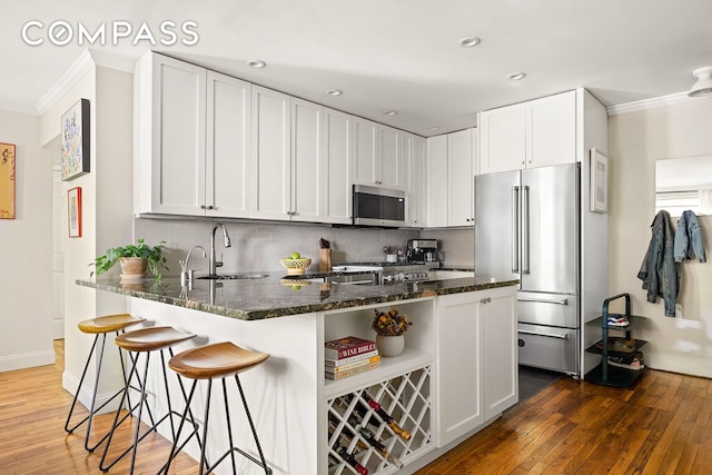 kitchen with appliances with stainless steel finishes, ornamental molding, backsplash, and a peninsula