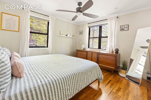 bedroom featuring light wood-style floors, multiple windows, and ornamental molding
