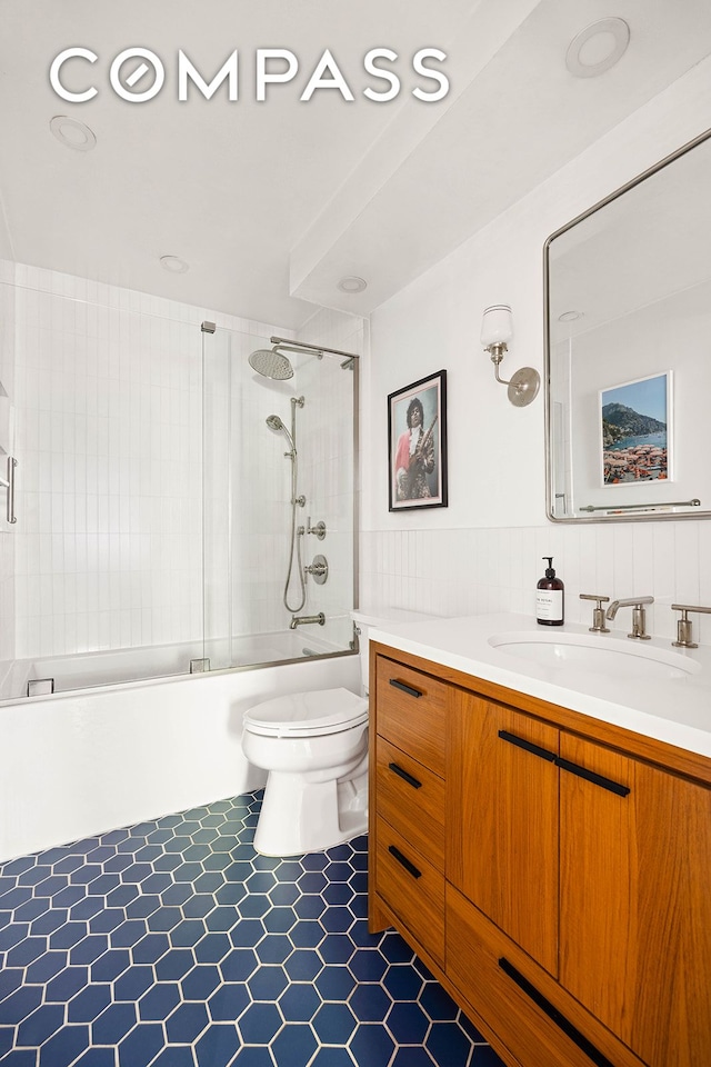 bathroom featuring tile patterned flooring, combined bath / shower with glass door, toilet, and vanity