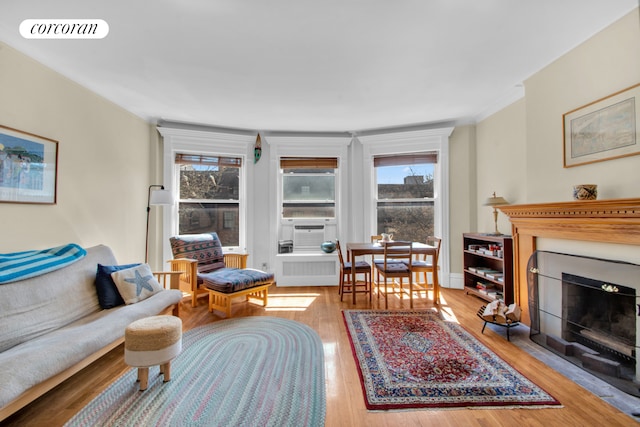 living room with a fireplace with flush hearth, wood finished floors, visible vents, and cooling unit