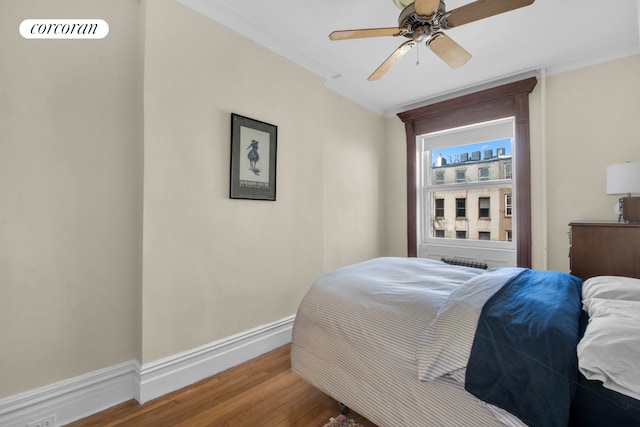 bedroom with baseboards, crown molding, ceiling fan, and wood finished floors