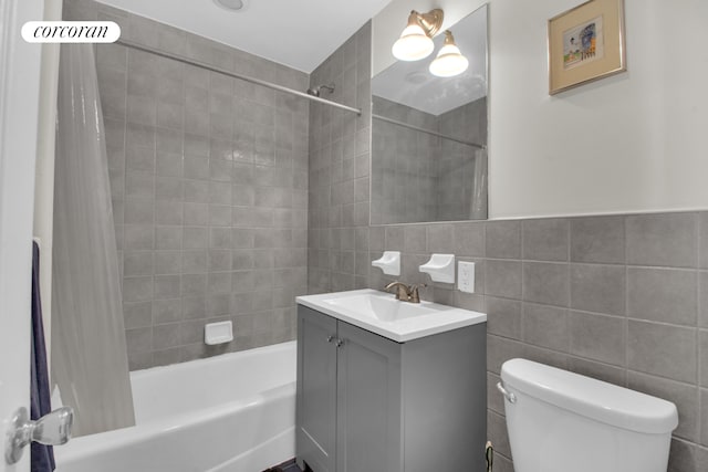 bathroom with tile walls, shower / bath combo with shower curtain, vanity, and toilet
