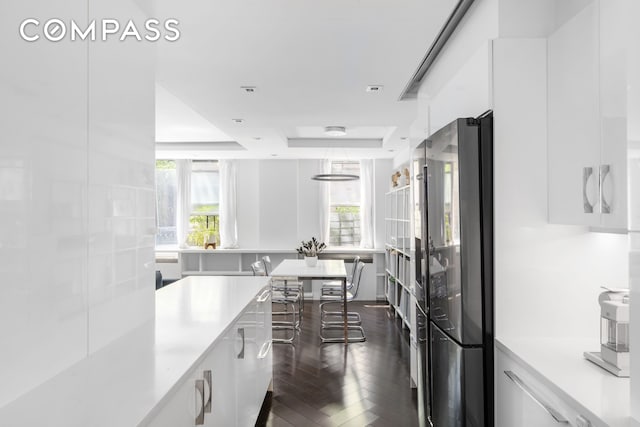 kitchen with freestanding refrigerator, white cabinetry, a tray ceiling, and modern cabinets