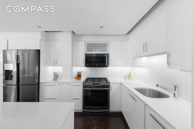 kitchen with appliances with stainless steel finishes, modern cabinets, a sink, light countertops, and white cabinetry