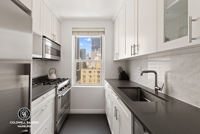 kitchen with a sink, white cabinets, dark countertops, and stainless steel appliances