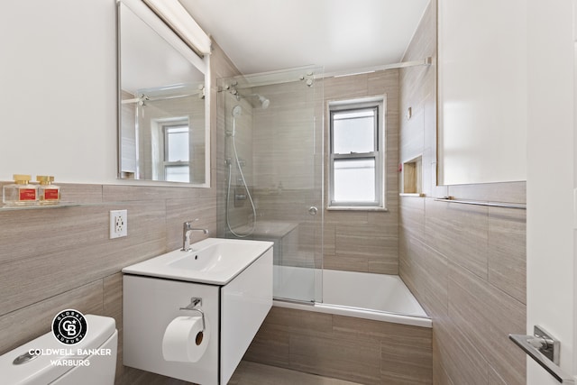 full bathroom featuring toilet, tile walls, a tile shower, and vanity