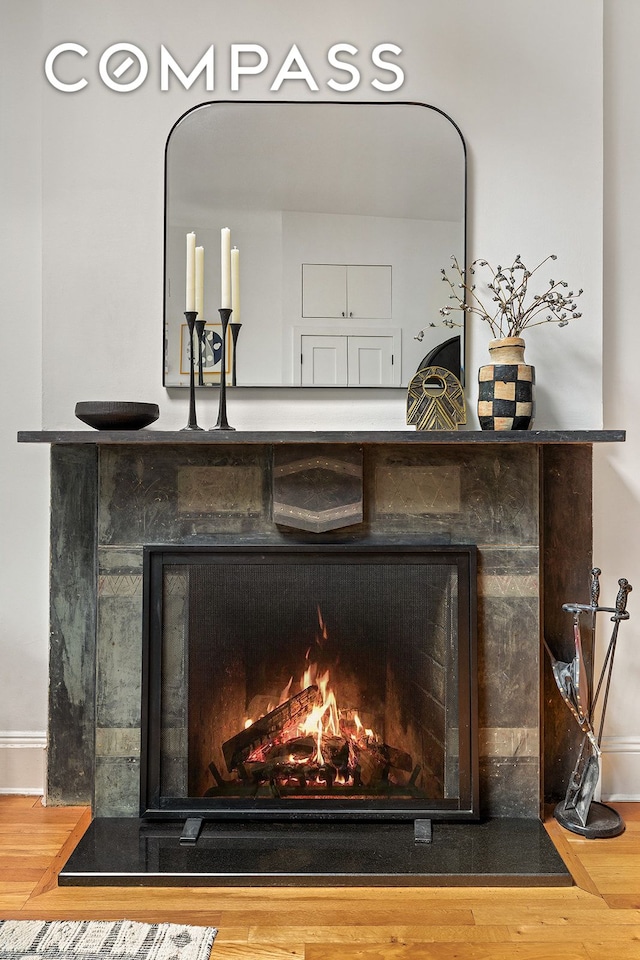 room details with baseboards, a lit fireplace, and wood finished floors
