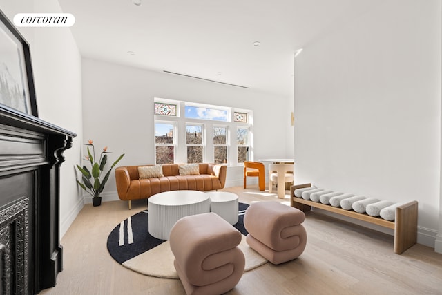 living area with baseboards, light wood-style flooring, visible vents, and a fireplace