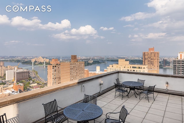 balcony with a city view, outdoor dining space, and a water view