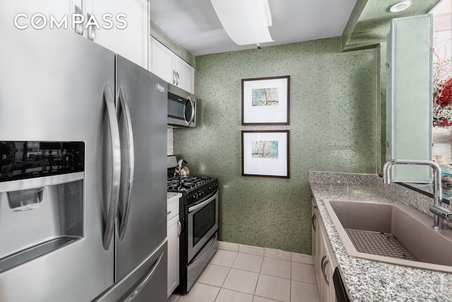 kitchen featuring white cabinetry, light tile patterned flooring, appliances with stainless steel finishes, and a sink