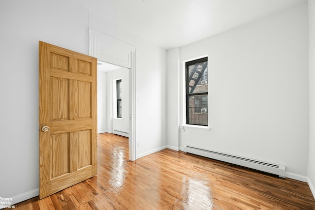empty room with light wood-type flooring, baseboards, and baseboard heating