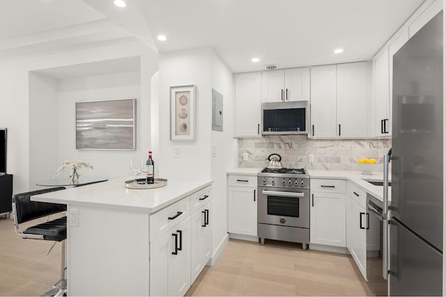kitchen with stainless steel appliances, light wood-type flooring, white cabinetry, tasteful backsplash, and recessed lighting