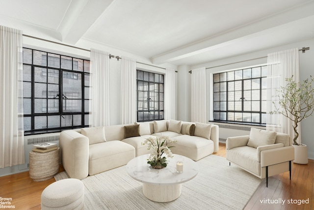 living area with a healthy amount of sunlight, beamed ceiling, and wood finished floors