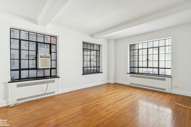 unfurnished room with beam ceiling, radiator heating unit, and hardwood / wood-style flooring