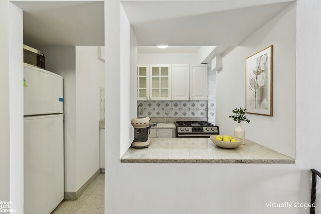 10 Park Ave Unit 5L, New York City, NY 10016 - kitchen featuring appliances with stainless steel finishes, glass insert cabinets, white cabinets, backsplash, and baseboards
