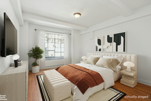 bedroom with baseboards, wood finished floors, and beam ceiling