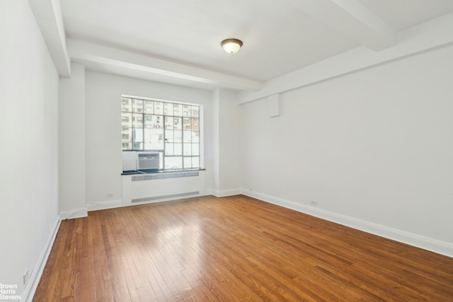spare room with beamed ceiling, baseboards, and wood-type flooring