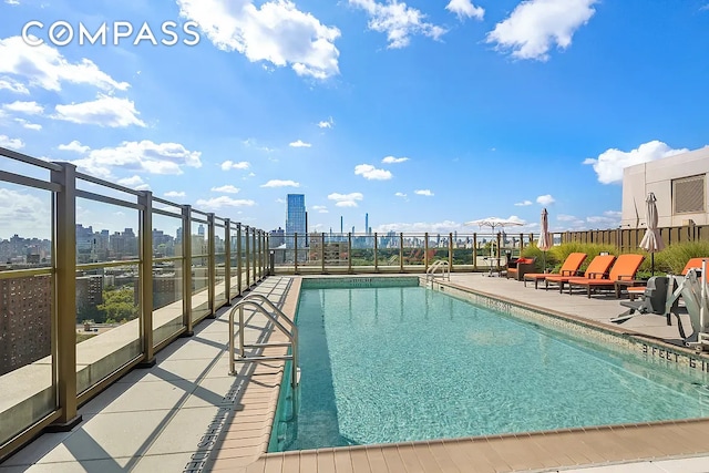 community pool featuring a patio, fence, and a city view