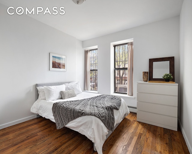 bedroom featuring baseboards, a baseboard heating unit, and wood finished floors