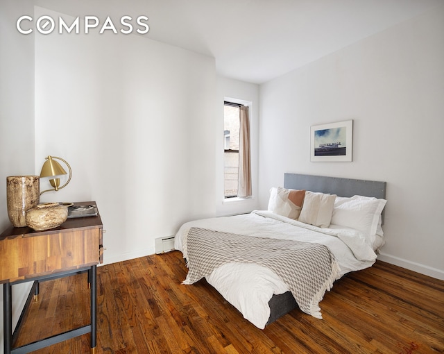 bedroom with baseboards, baseboard heating, and wood finished floors