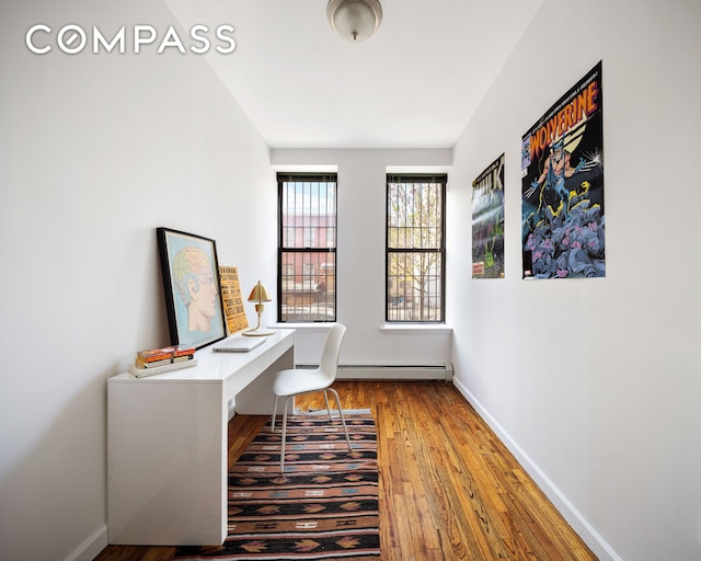 home office featuring baseboards, a baseboard heating unit, and wood finished floors